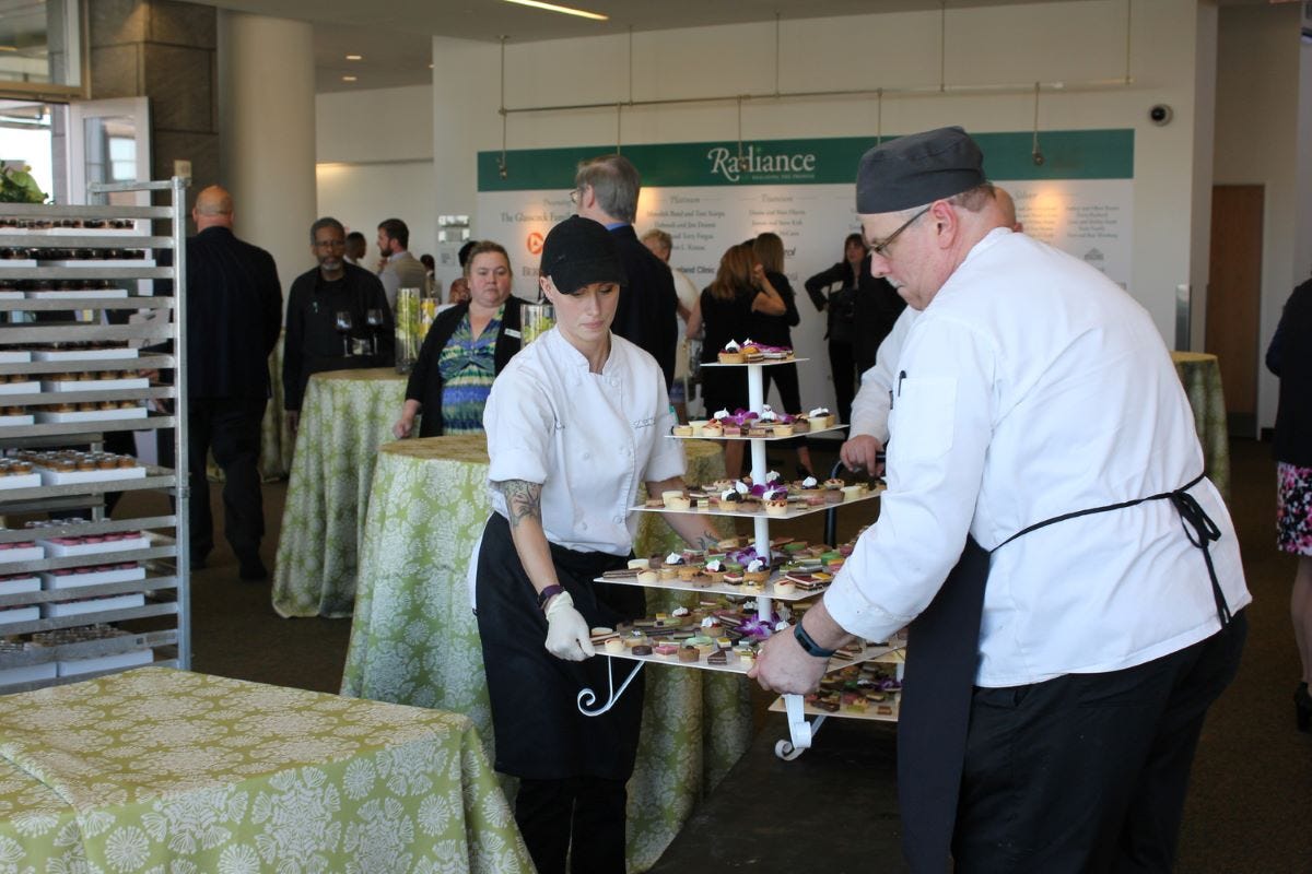 Culinary team carrying a 5-tier cupcake tower with desserts on it into place